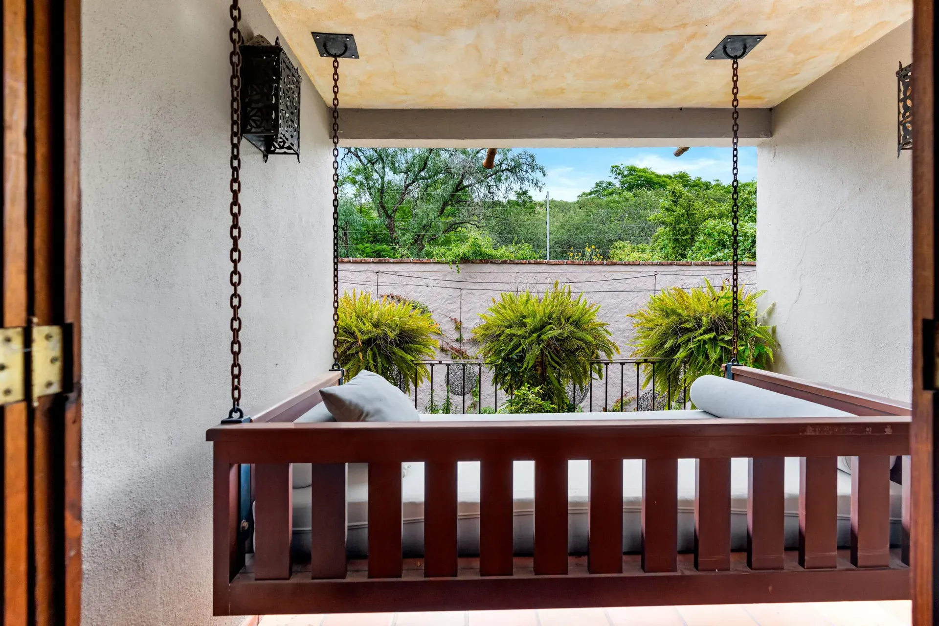 Casa Roka, balcony with a hanging porch swing, potted ferns and a view of trees, San Miguel de Allende