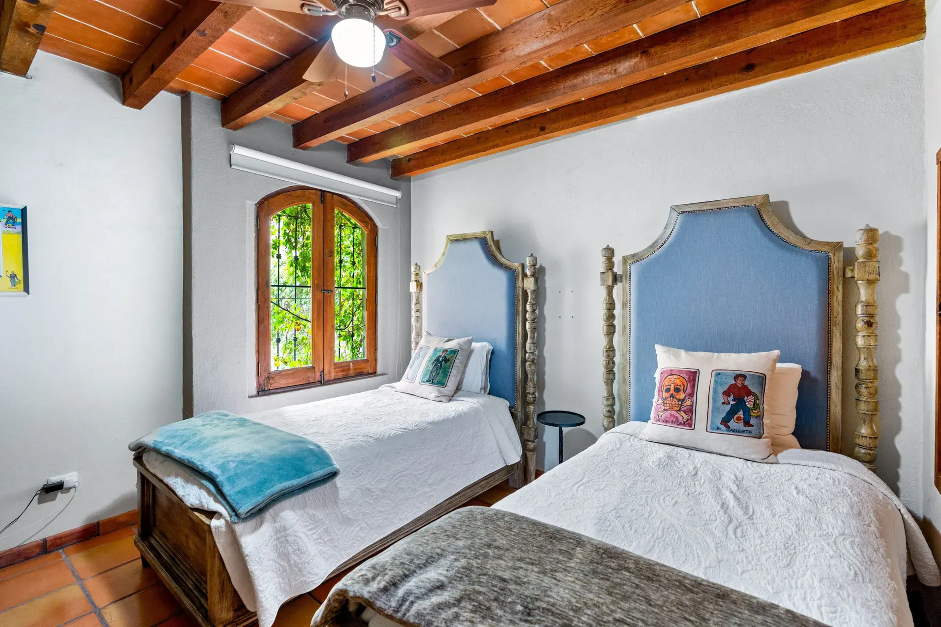 Casa Roka, twin bedroom with blue upholstered headboards, white bedspreads and a ceiling fan, San Miguel de Allende
