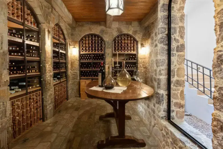 Casa Ronda, wine cellar with stone arches, wine racks, a wood ceiling and a round table with glass decanters, San Miguel de Allende