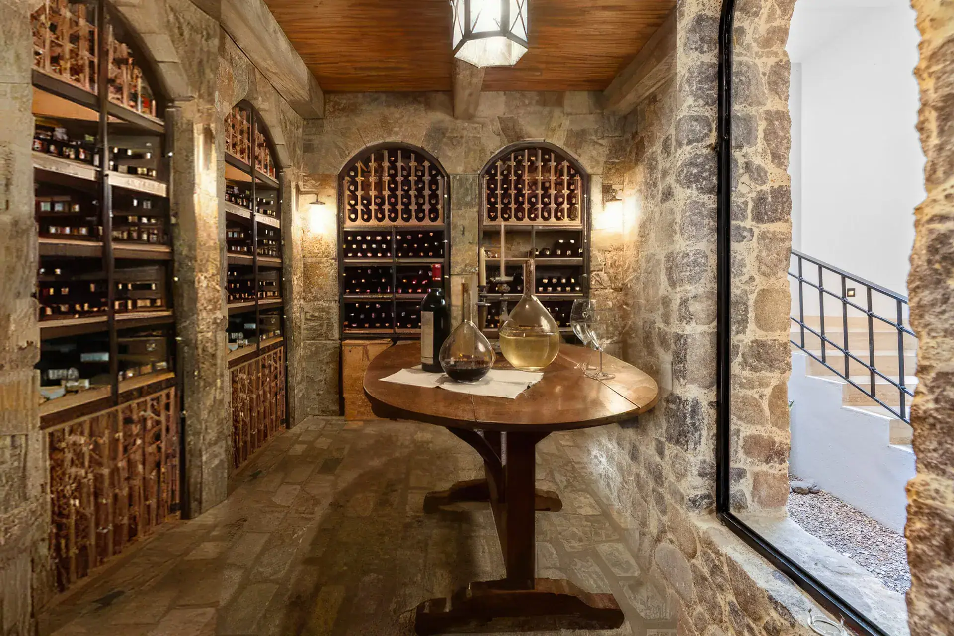 Casa Ronda, wine cellar with stone arches, wine racks, a wood ceiling and a round table with glass decanters, San Miguel de Allende