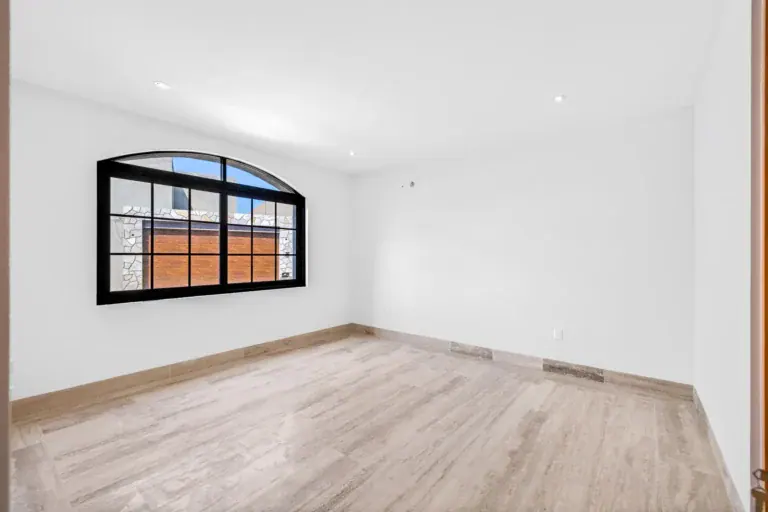 Casa Ronda, empty room with an arched black-framed window and a pale wood floor, San Miguel de Allende