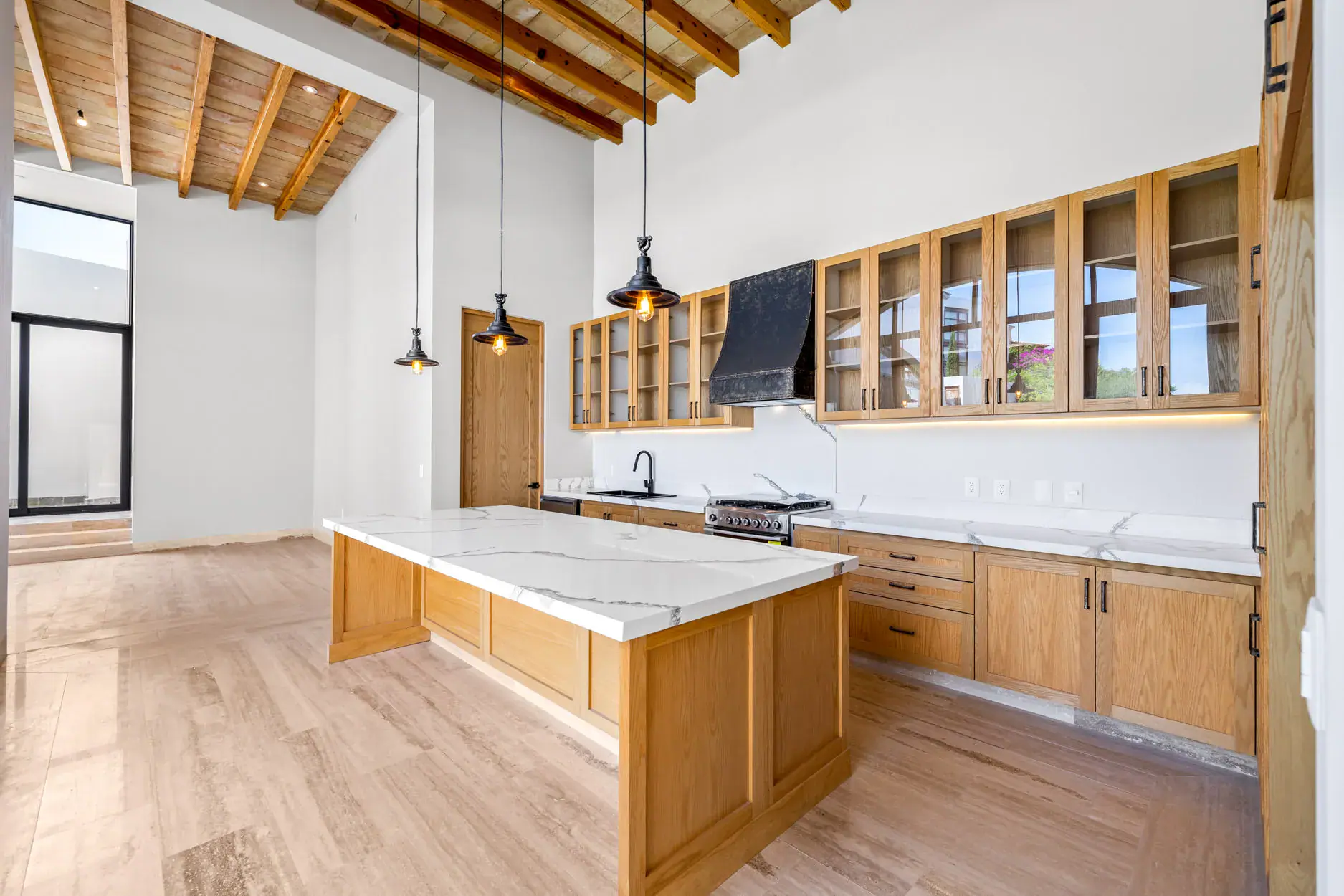 Casa Ronda, open kitchen with a wood island with a marble top, glass-fronted wood cabinets and a wood beam ceiling, San Miguel de Allende