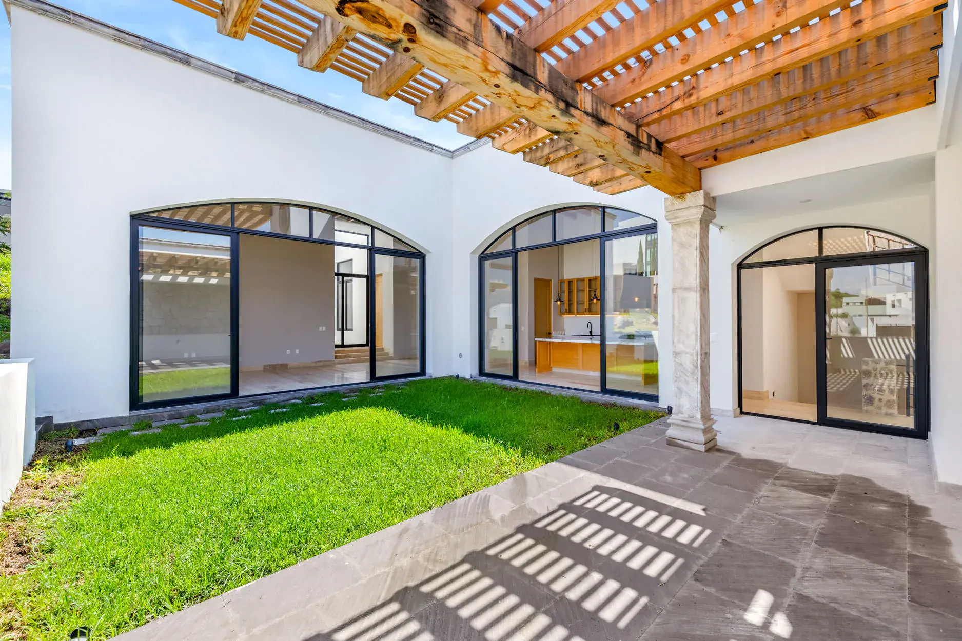 Casa Ronda, courtyard lawn with stepping stones, a pergola and arched glass doors on the house, San Miguel de Allende