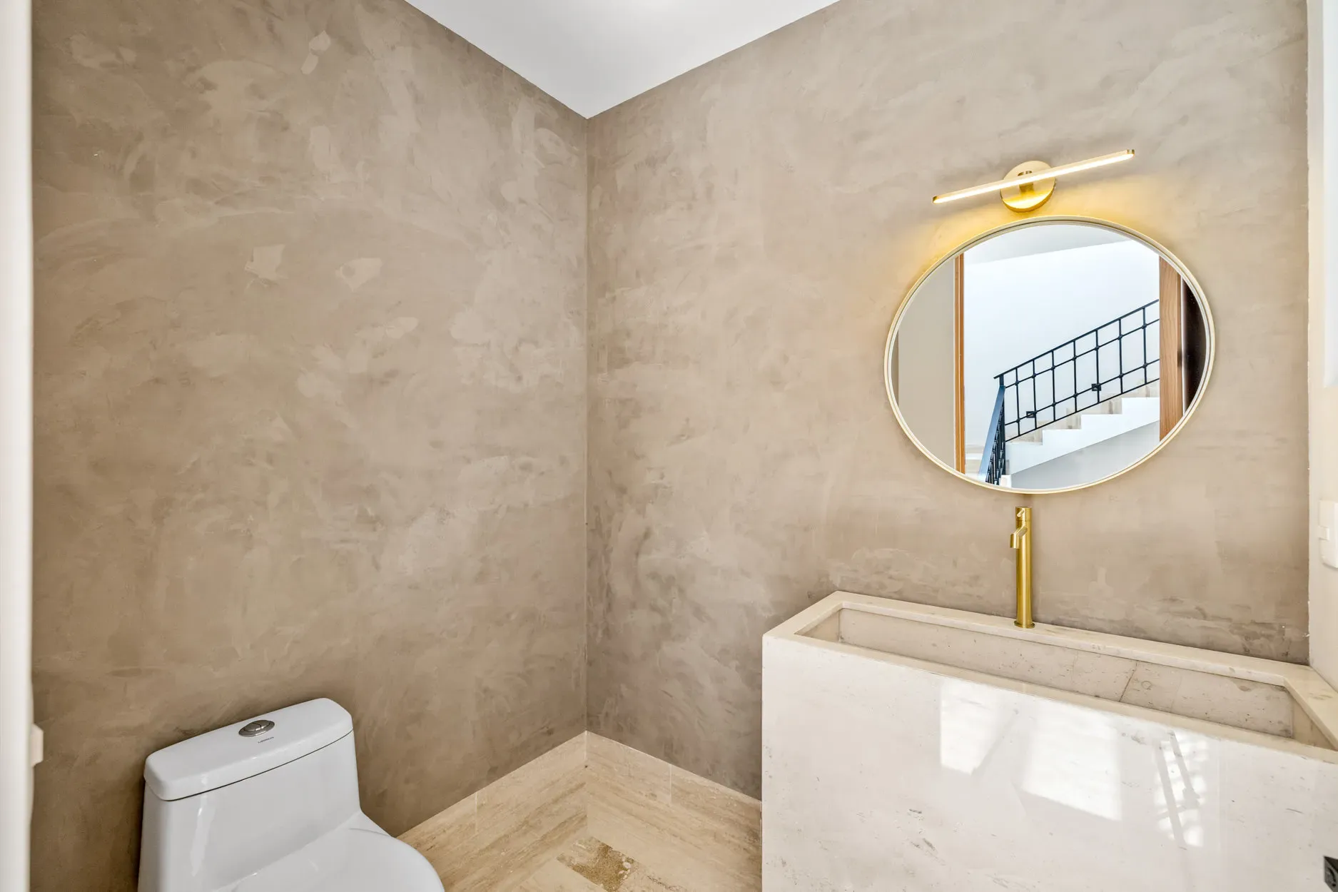 Casa Ronda, powder room with a gold-framed round mirror, a stone sink and plaster walls, San Miguel de Allende