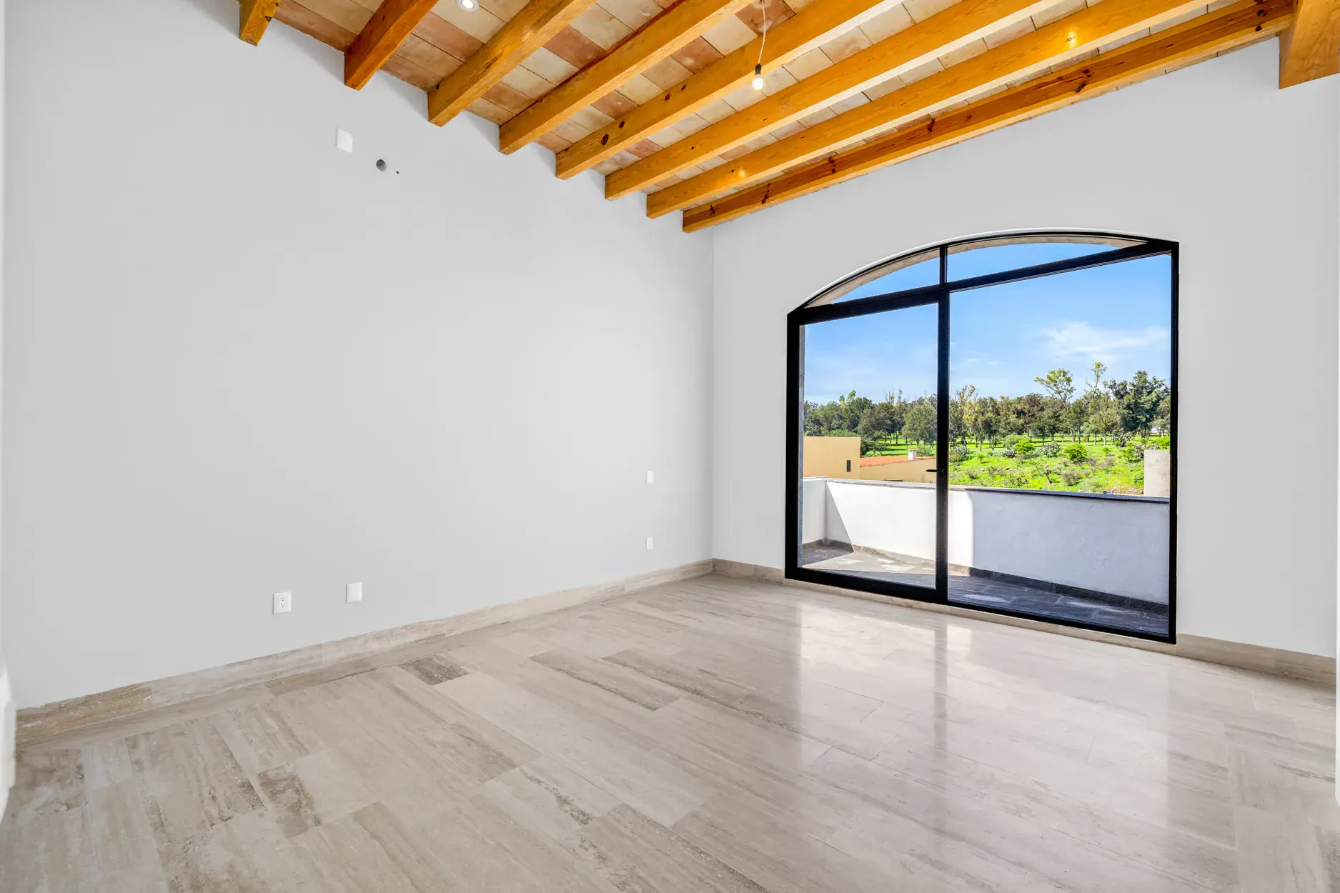 Casa Ronda, empty bedroom with a wood beam ceiling and an arched window to the hills, San Miguel de Allende