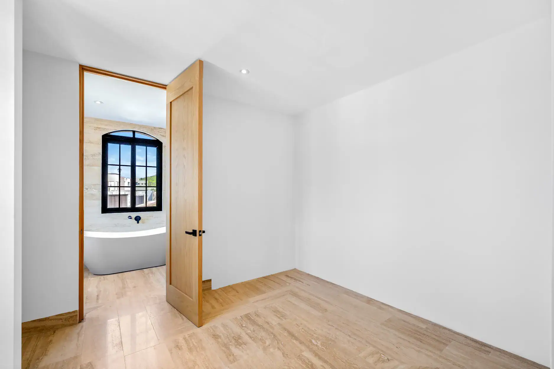 Casa Ronda, empty room with a wood door to a bathroom with a freestanding tub, San Miguel de Allende