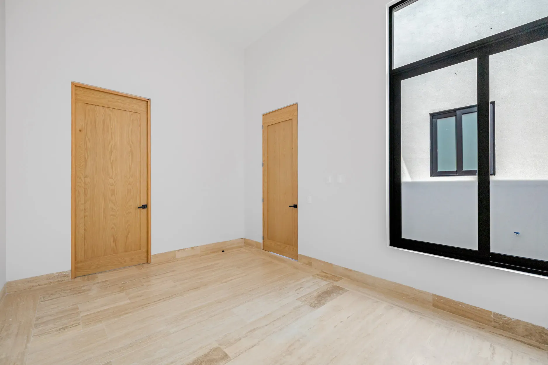 Casa Ronda, empty bedroom with a wood door and a black-framed window, San Miguel de Allende