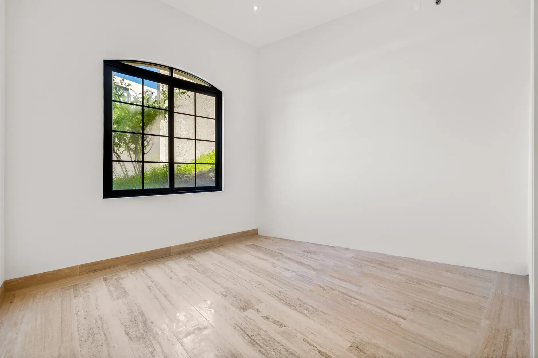 Casa Ronda, empty bedroom with a black-framed arched window with garden views, San Miguel de Allende