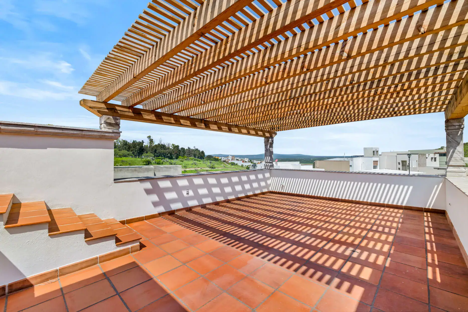 Casa Ronda, rooftop terrace with a wood pergola, terracotta floor, steps and views of the hills, San Miguel de Allende