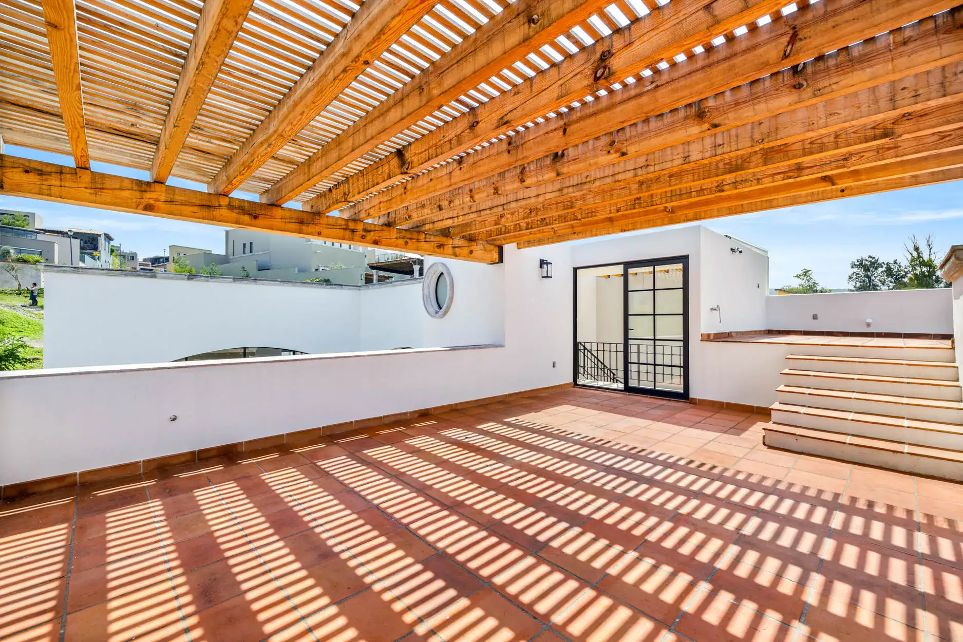 Casa Ronda, rooftop terrace with a wood slat pergola, terracotta tile and a glass door, San Miguel de Allende