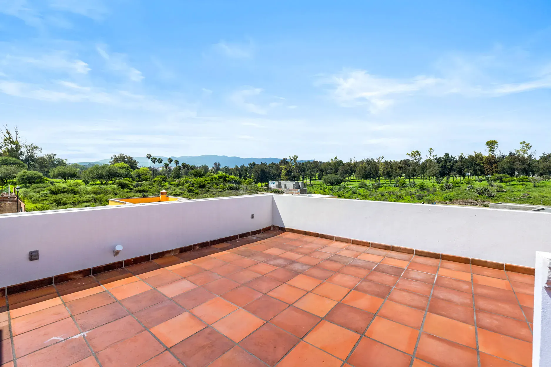 Casa Ronda, rooftop terrace with a terracotta floor and a view of green fields and mountains, San Miguel de Allende