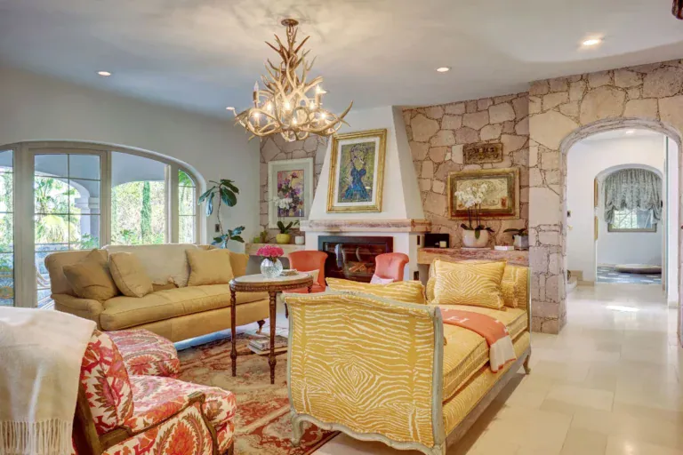 Casa Rosa, living room with a stone fireplace, yellow sofa and a floral chandelier, San Miguel de Allende