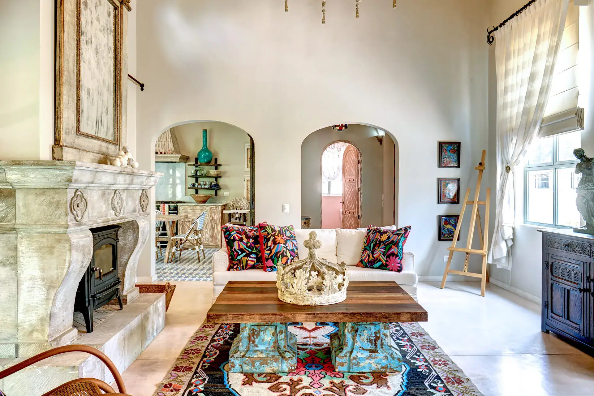 Casa Rosa, living room with a stone fireplace, a gray sofa and a colorful rug, San Miguel de Allende