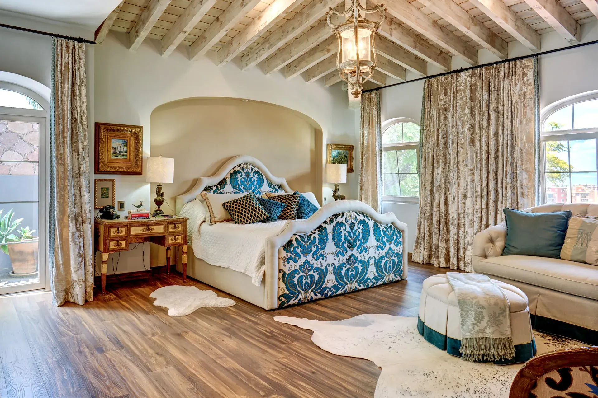 Casa Rosa, bedroom with a blue upholstered headboard and arched windows, San Miguel de Allende