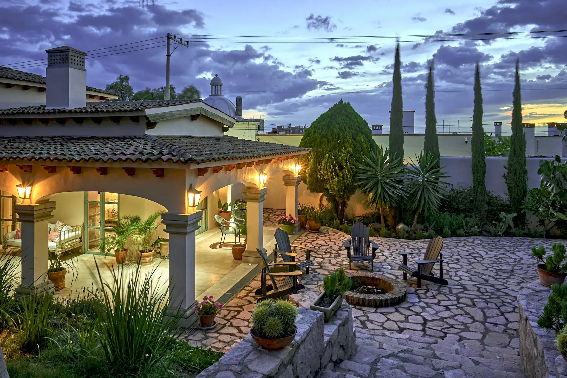Casa Rosa, garden patio with a fire pit and a covered porch at dusk, San Miguel de Allende