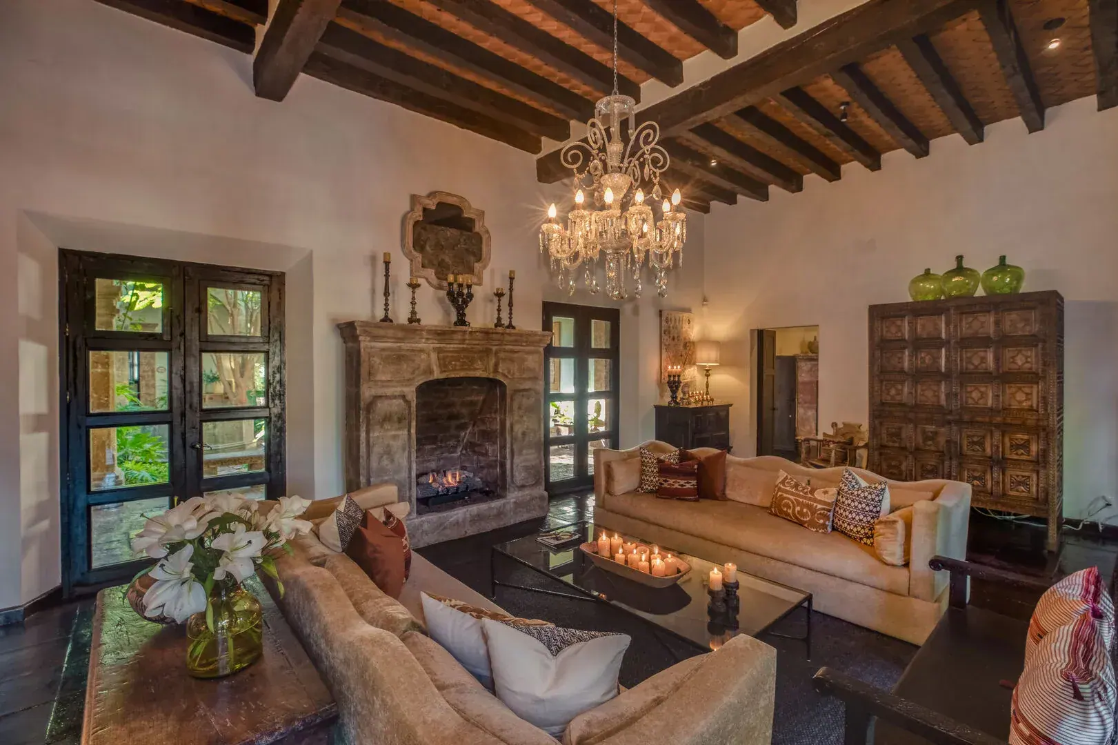 Casa San Jose, living room with a stone fireplace, chandelier and tan sofas, San Miguel de Allende