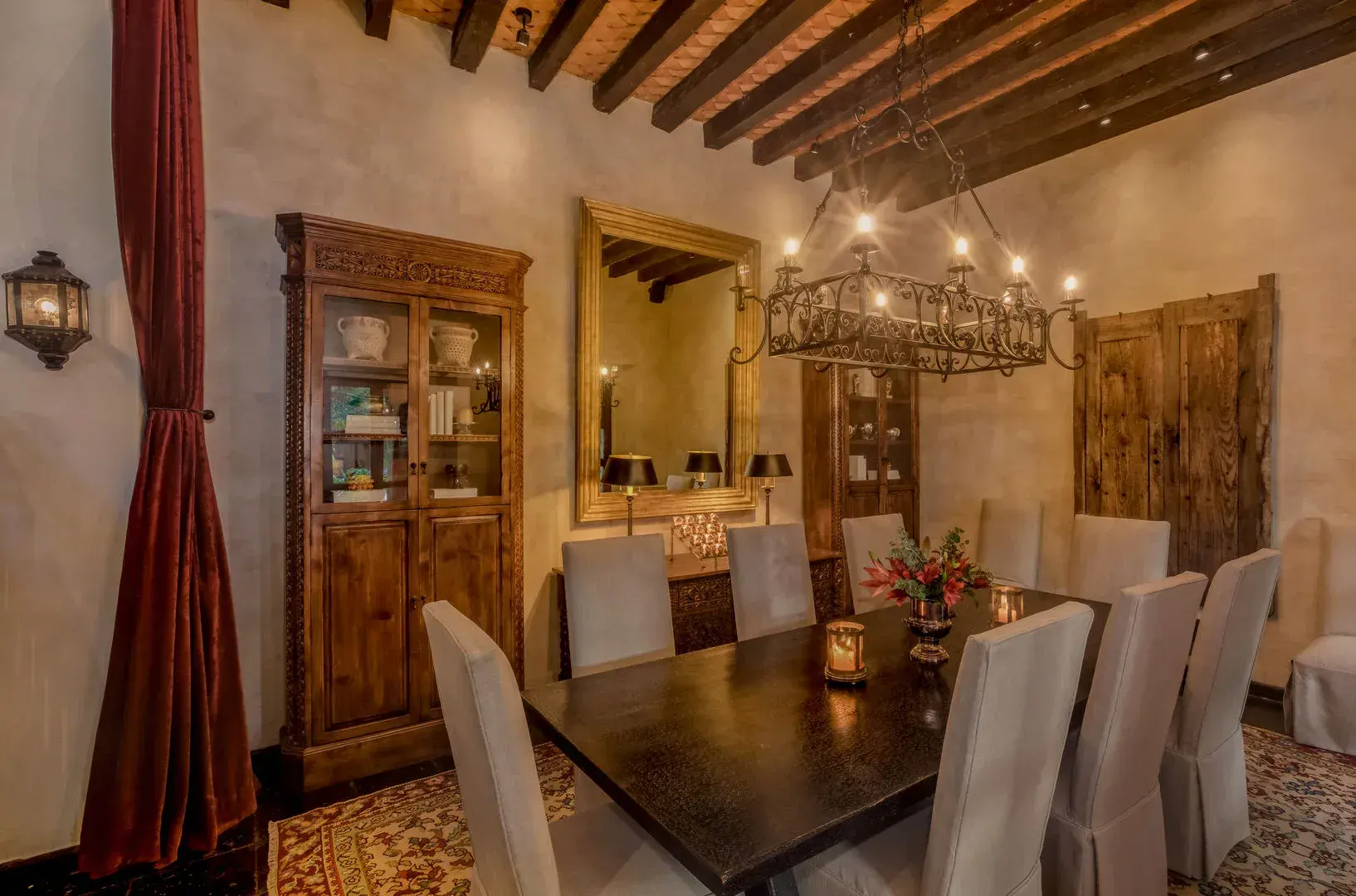 Casa San Jose, dining room with a dark wood table, iron chandelier and carved cabinets, San Miguel de Allende