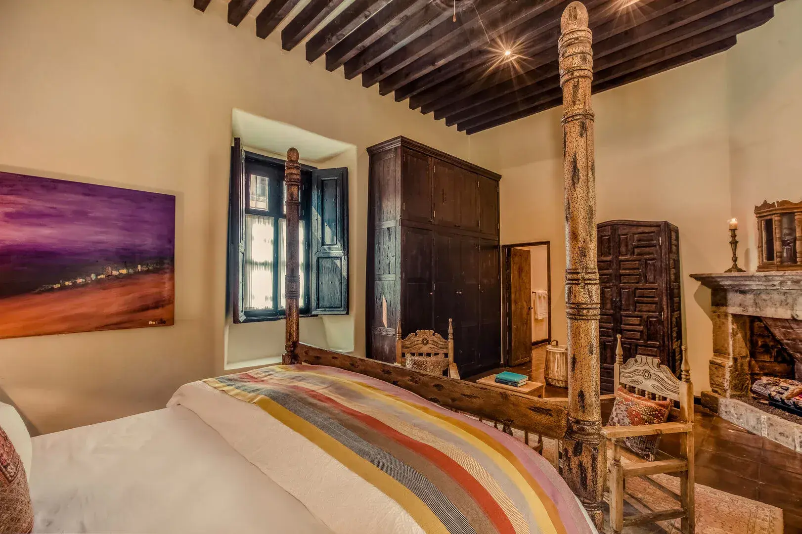 Casa San Jose, primary bedroom with a carved four-poster bed and striped blanket, San Miguel de Allende