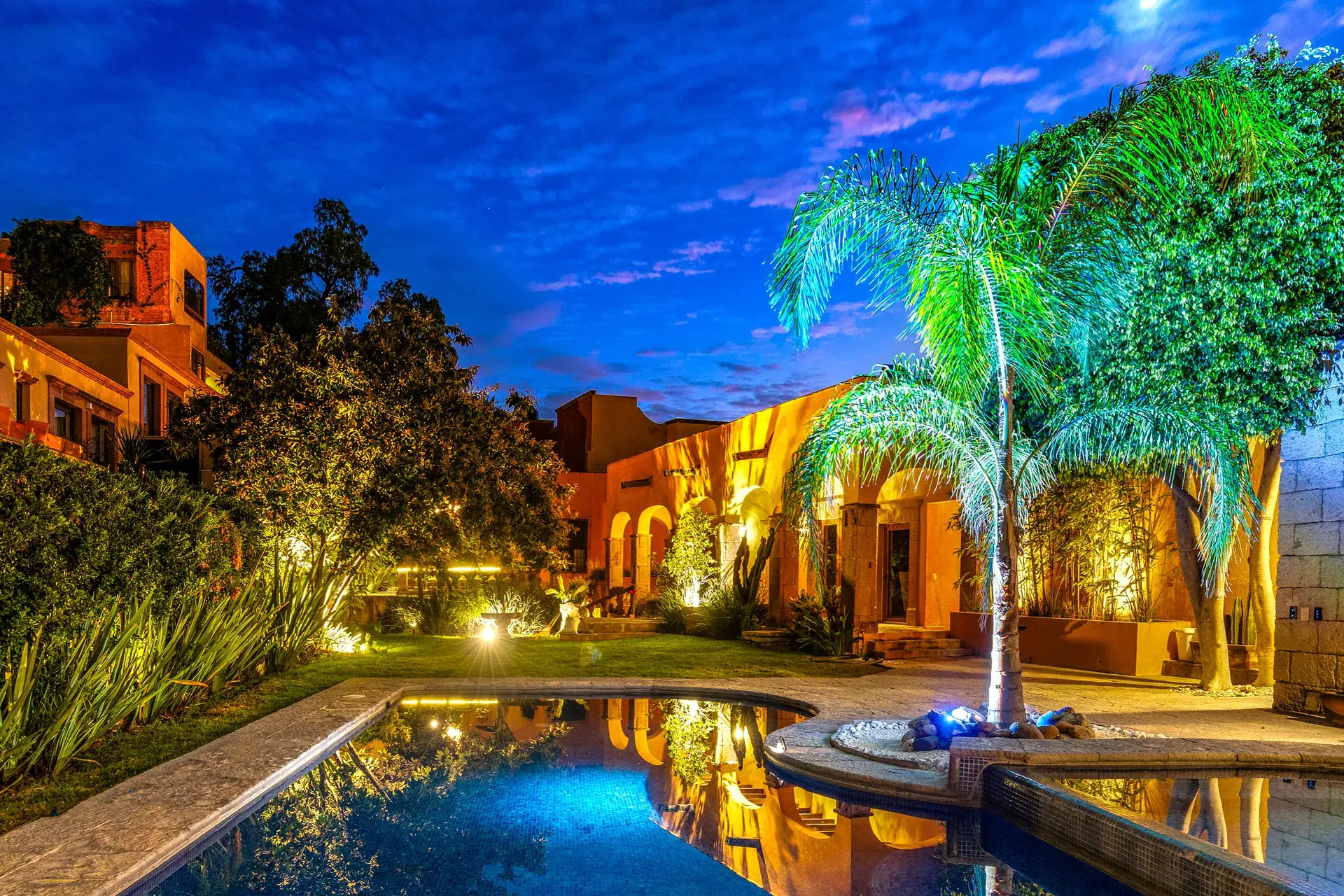 Casa San Rafael, courtyard pool and palm trees glowing at night, San Miguel de Allende