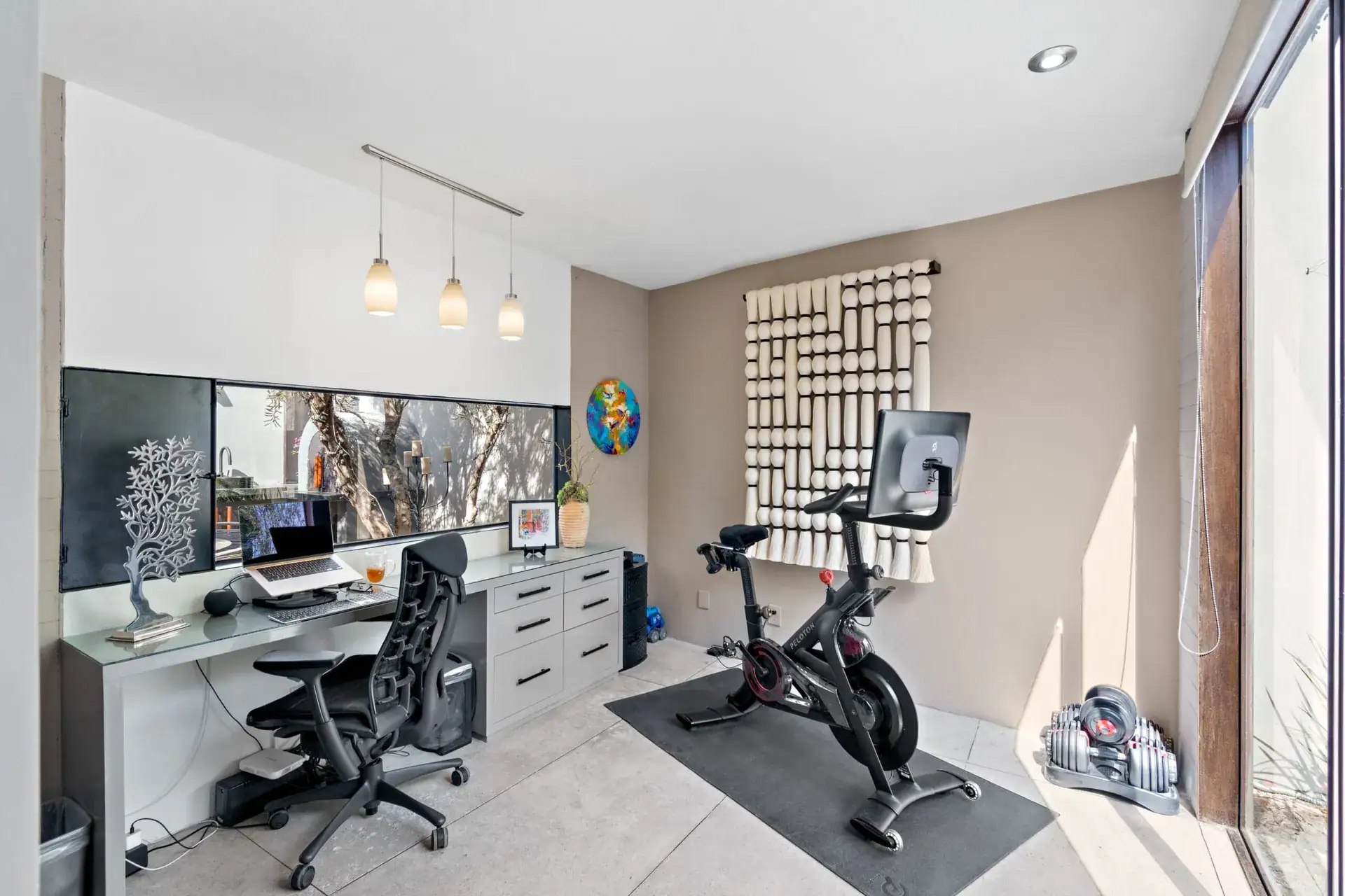 Casa Sanchez Renero, home office with a desk, a stationary bike, wall sculpture and a glass door to a courtyard, San Miguel de Allende