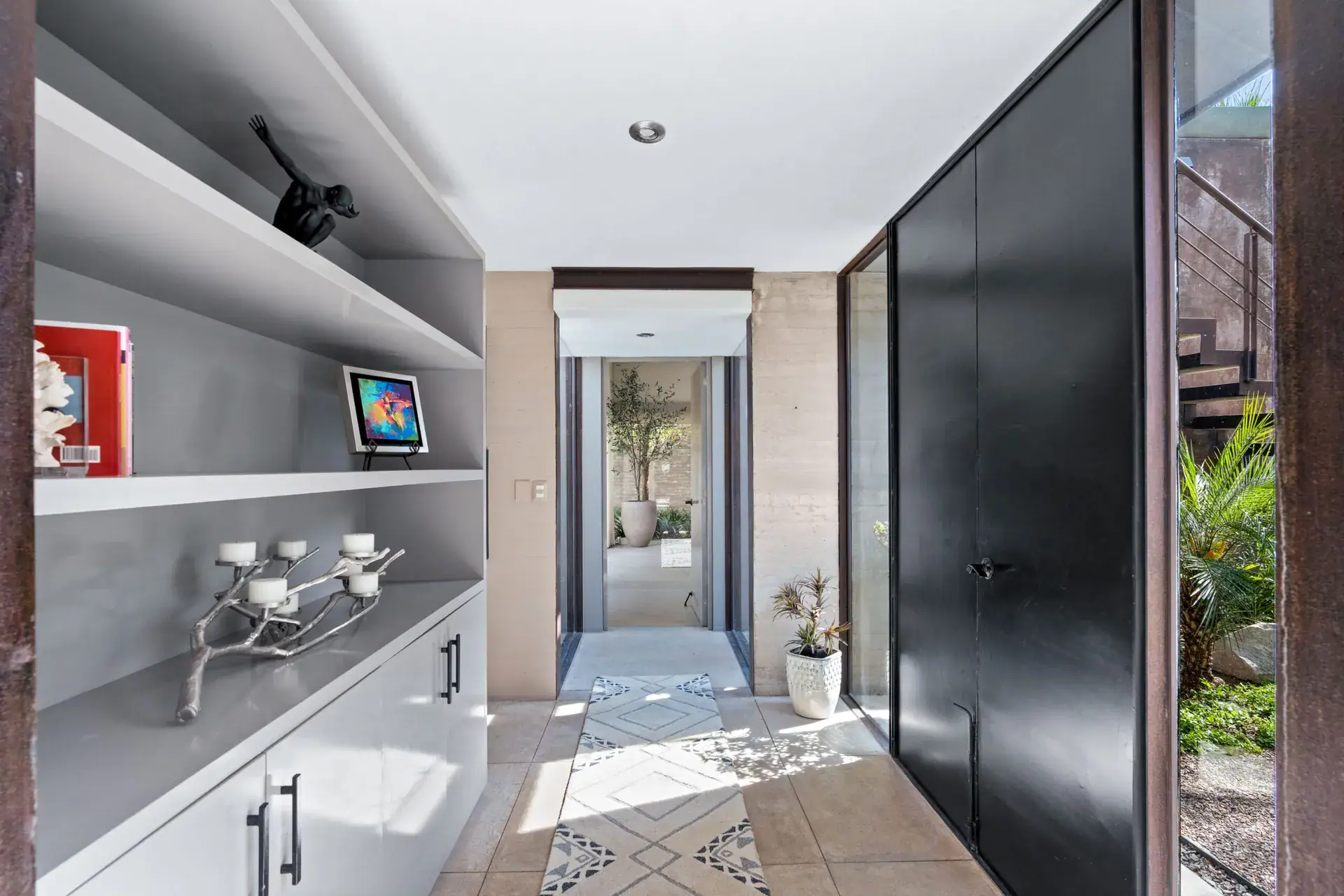 Casa Sanchez Renero, hallway with built-in shelves, a black cabinet and a view down a tiled corridor, San Miguel de Allende