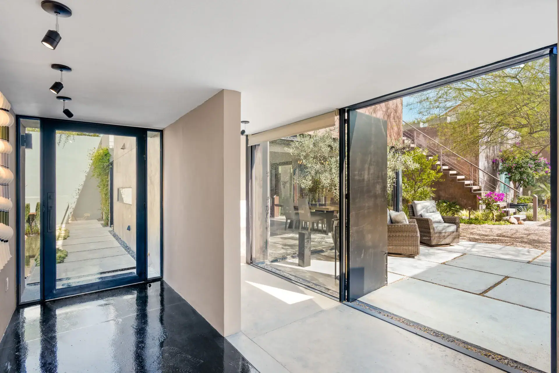 Casa Sanchez Renero, entry foyer with a black-framed glass door, a black glossy floor and a view to the courtyard, San Miguel de Allende
