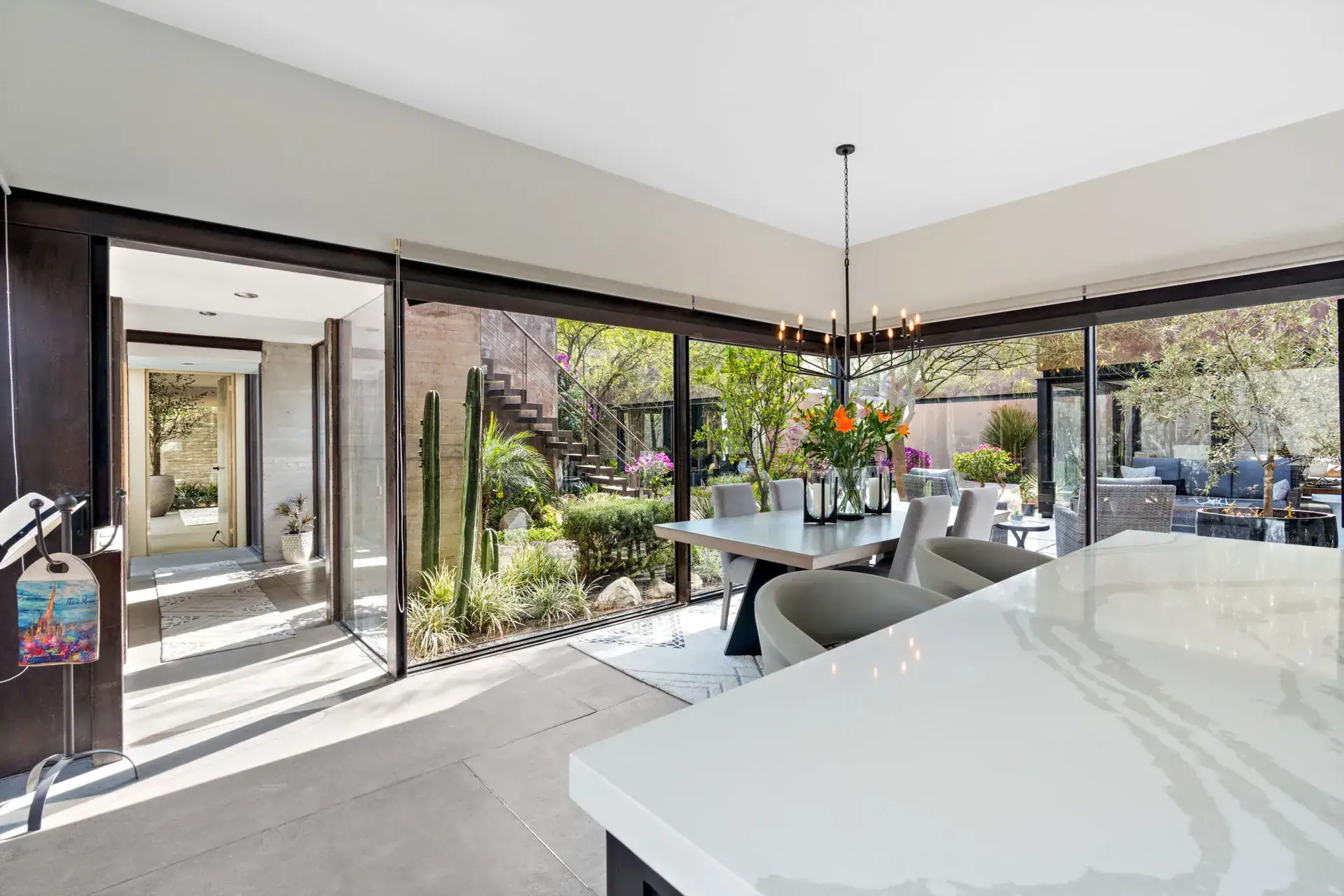 Casa Sanchez Renero, dining area and corner glass wall with a quartz counter in the foreground and a corridor beyond, San Miguel de Allende