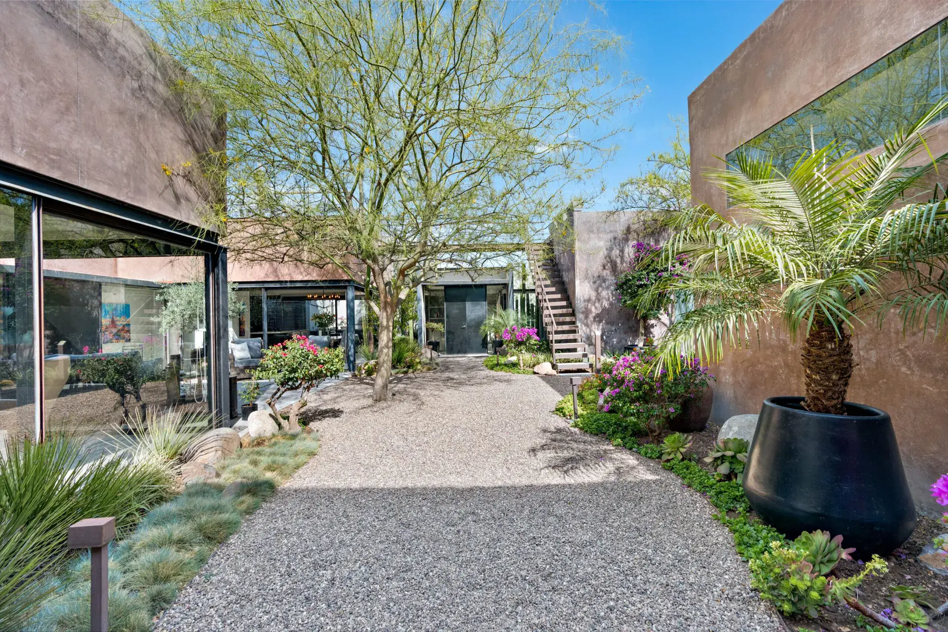 Casa Sanchez Renero, gravel path through a desert garden to a staircase and a copper-toned building, San Miguel de Allende