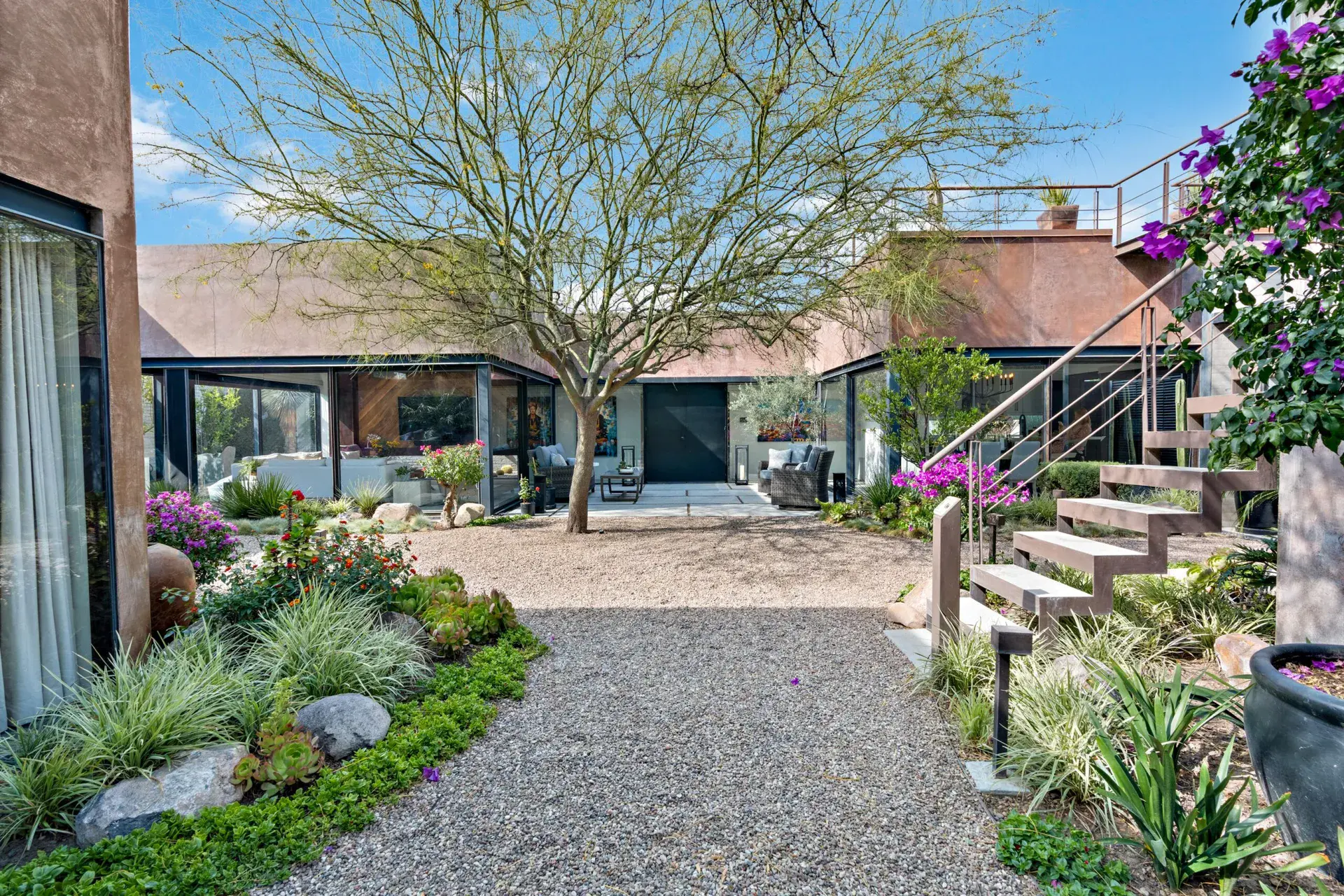 Casa Sanchez Renero, courtyard with a gravel path, a tree and a steel staircase leading up to the roof, San Miguel de Allende