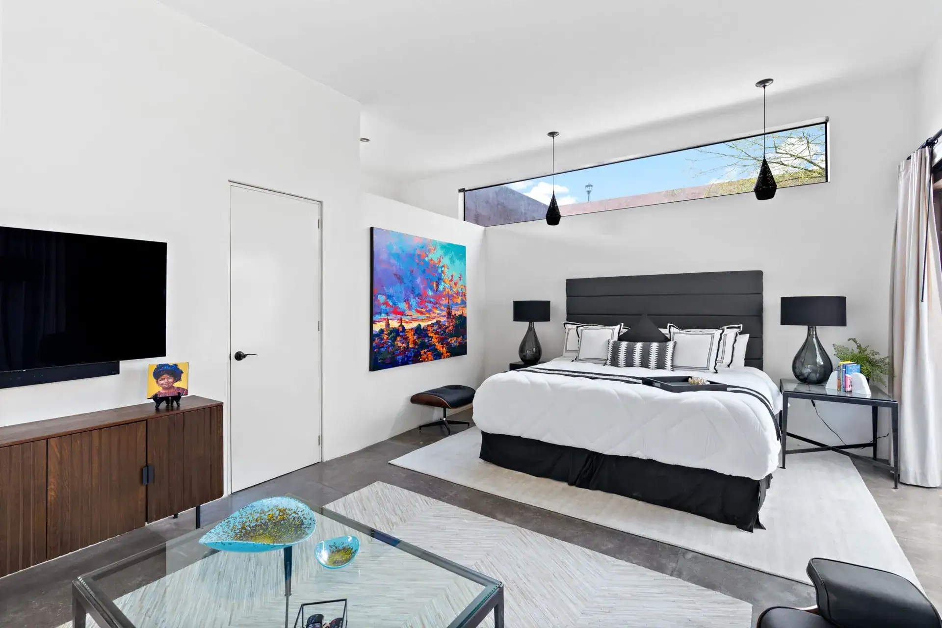 Casa Sanchez Renero, bedroom with a black headboard, white bedding, a wall-mounted television and a large painting, San Miguel de Allende
