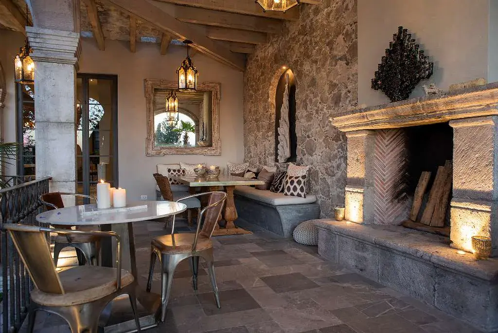 Casa Sereno, covered terrace with a stone fireplace, bistro table and built-in bench, San Miguel de Allende