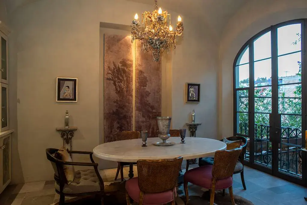 Casa Sereno, dining area with a round table, a gold chandelier and arched glass doors, San Miguel de Allende