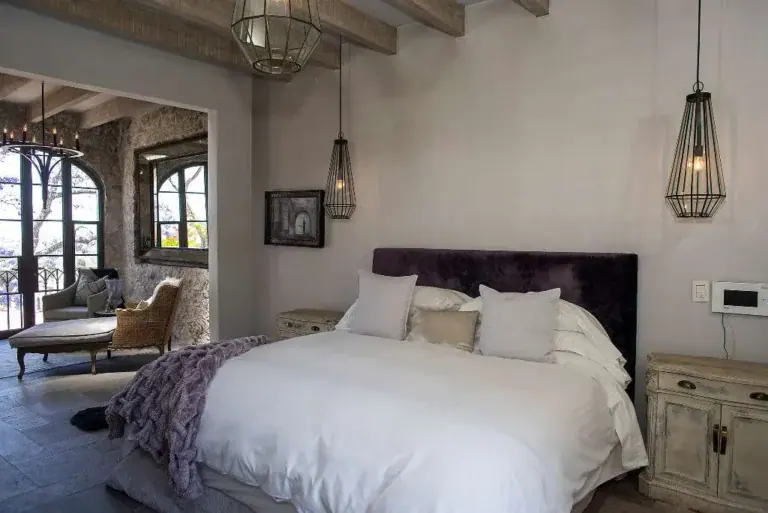 Casa Sereno, bedroom with an upholstered headboard and a view into the sitting area, San Miguel de Allende