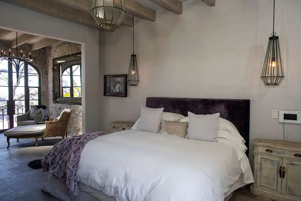 Casa Sereno, bedroom with an upholstered headboard and a view into the sitting area, San Miguel de Allende
