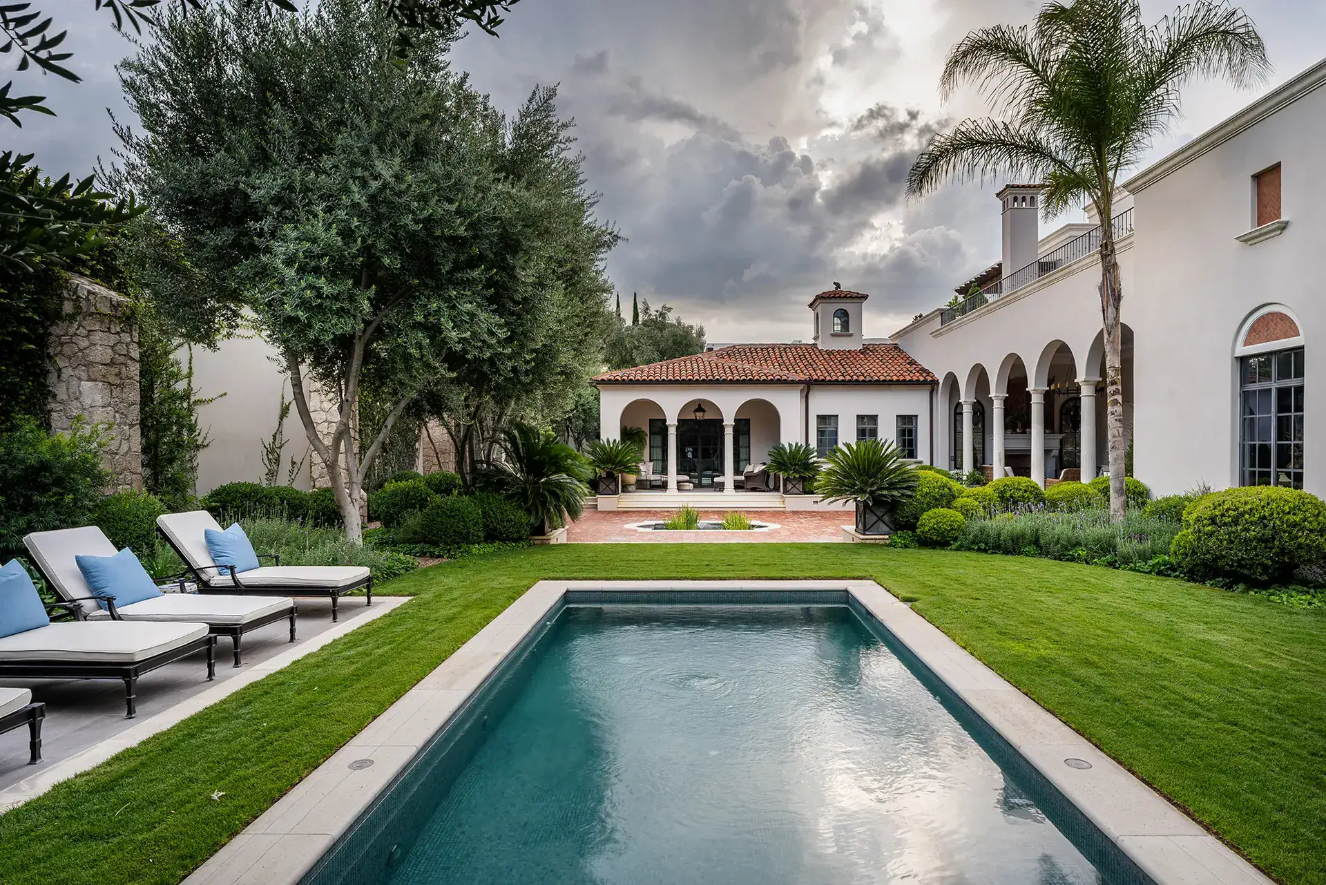 Casa Sienna, rectangular pool and lounge chairs on a green lawn in front of the Mediterranean-style house with arcades, San Miguel de Allende