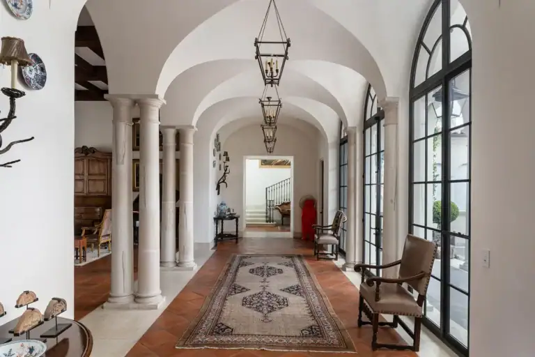 Casa Sienna, vaulted entrance gallery with stone columns, a runner rug and tall arched glass doors, San Miguel de Allende