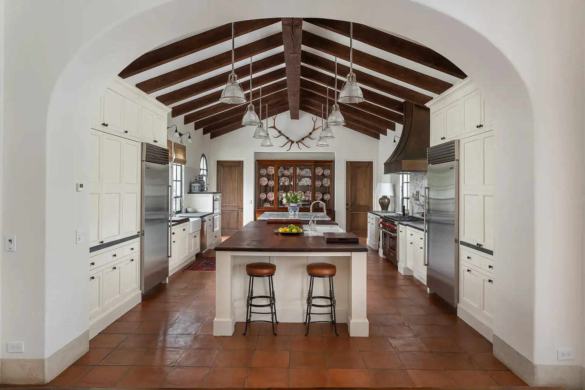 Casa Sienna, kitchen with a vaulted beamed ceiling, white cabinetry and a wood-topped island with stools, San Miguel de Allende