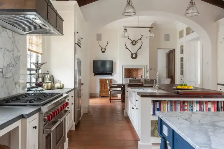 Casa Sienna, kitchen with a professional range, marble counters and a television beside antler mounts, San Miguel de Allende
