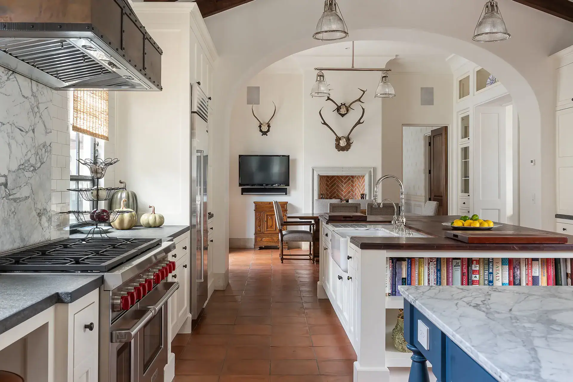 Casa Sienna, kitchen with a professional range, marble counters and a television beside antler mounts, San Miguel de Allende