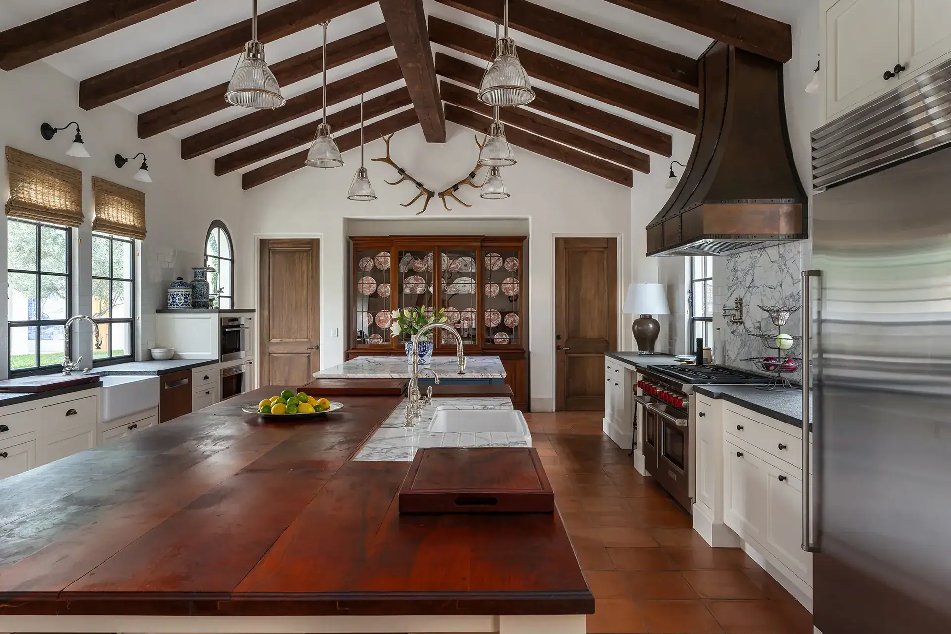 Casa Sienna, kitchen island with a wood counter beneath a beamed ceiling and a copper range hood, San Miguel de Allende