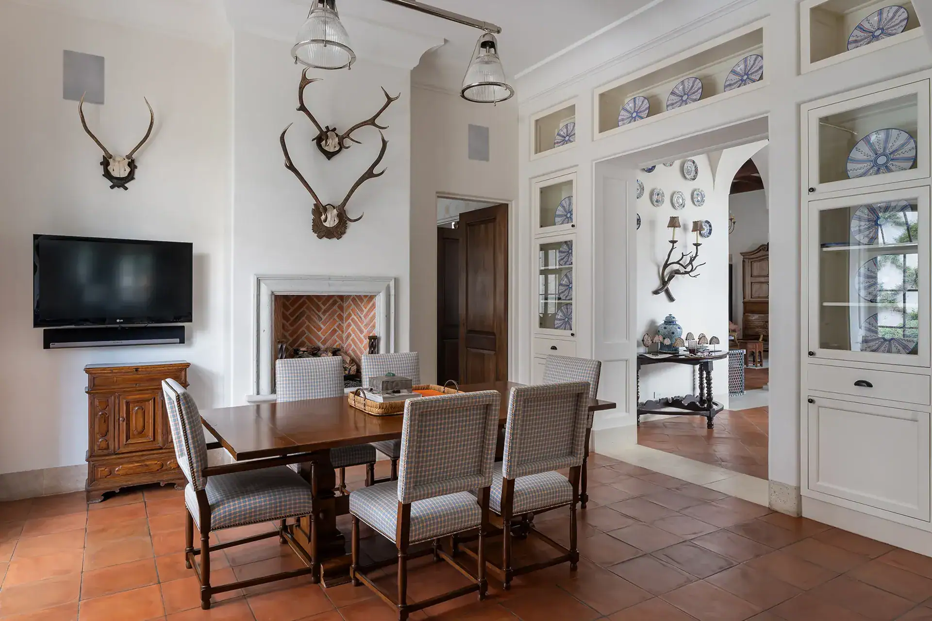 Casa Sienna, breakfast area with a wooden table, upholstered chairs and glass-fronted cabinets of blue and white china, San Miguel de Allende