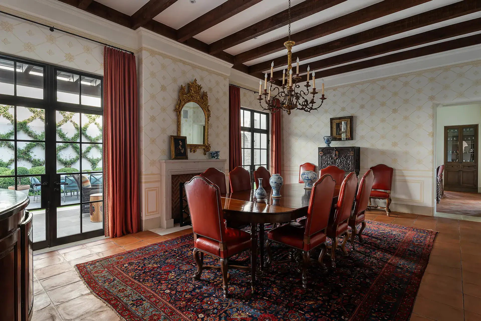 Casa Sienna, formal dining room with an oval table, red leather chairs and an oriental rug beside garden doors, San Miguel de Allende
