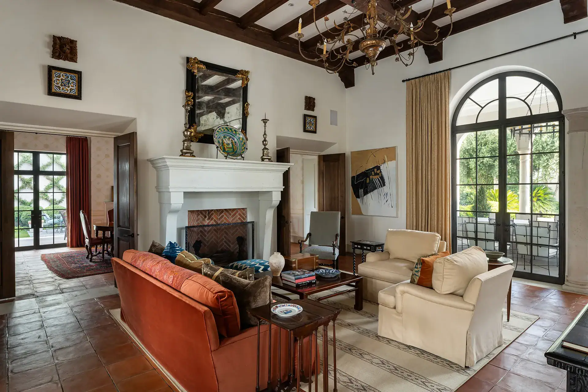 Casa Sienna, living room with a stone fireplace, rust sofa and arched glass doors to the garden, San Miguel de Allende