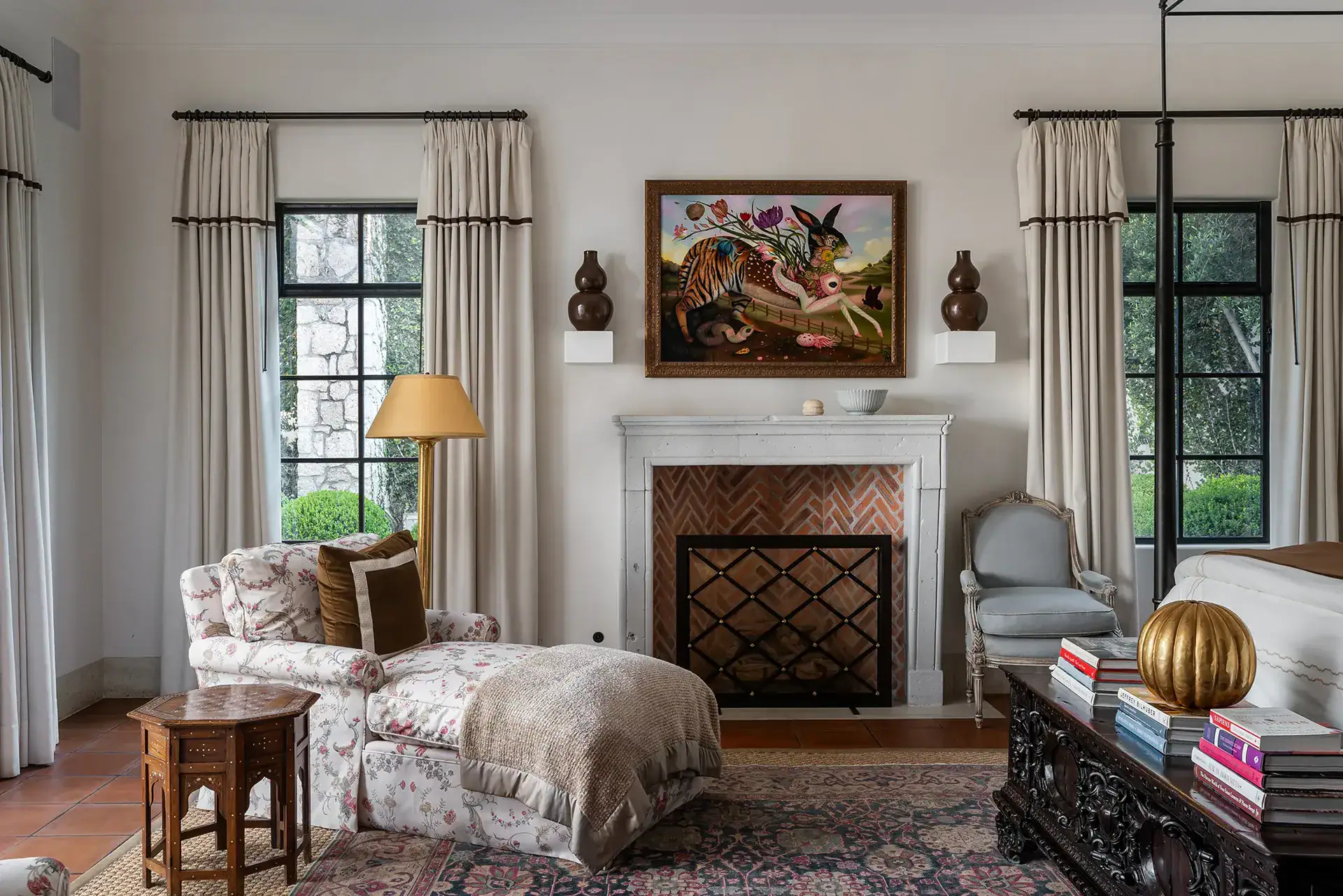 Casa Sienna, bedroom sitting area with a fireplace, floral chaise and a colorful painting, San Miguel de Allende