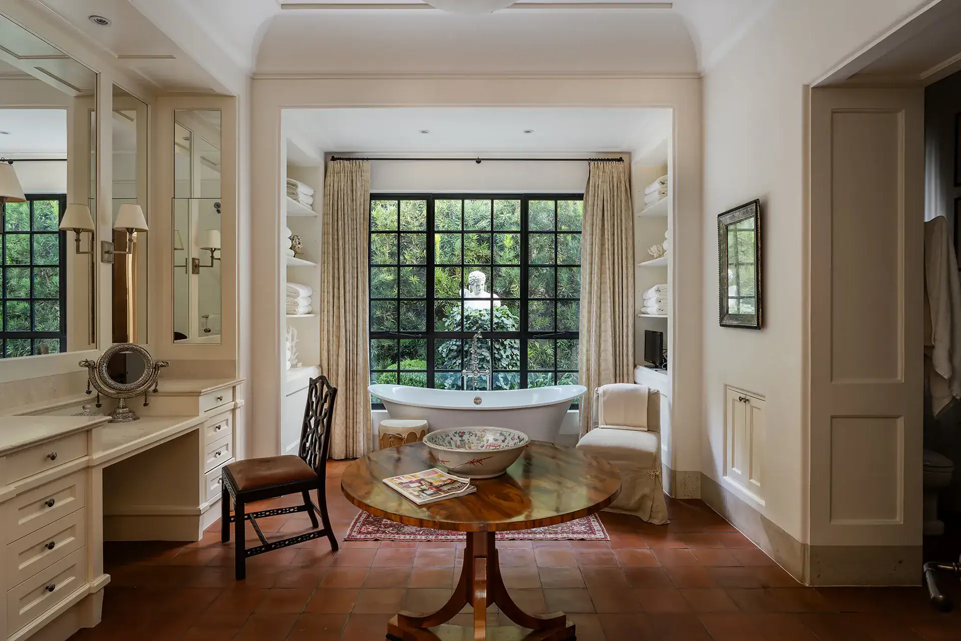 Casa Sienna, bathroom with a freestanding tub in front of a black-framed window and a vanity seat, San Miguel de Allende