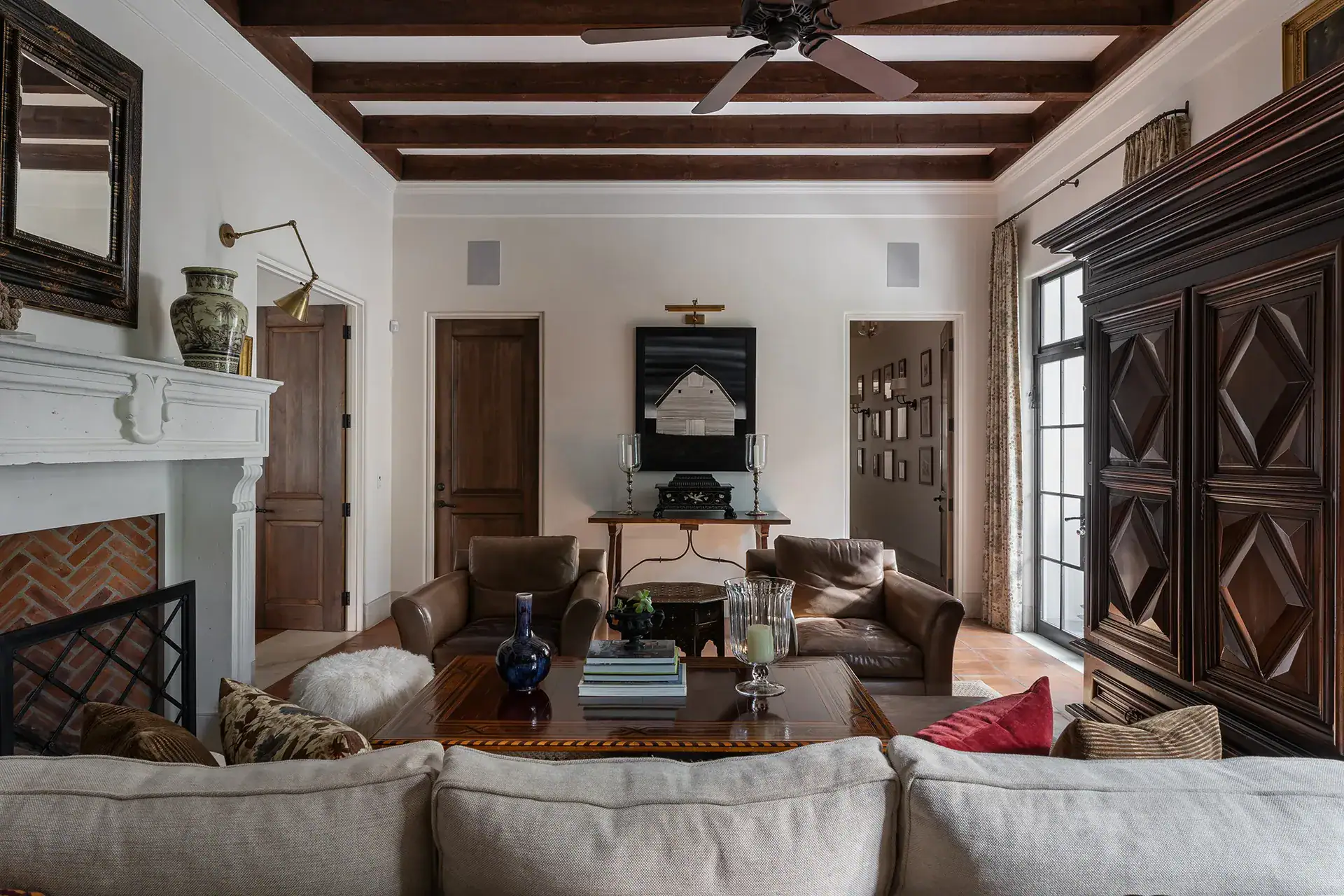 Casa Sienna, den with leather armchairs, a sofa, a fireplace and a carved wooden armoire, San Miguel de Allende