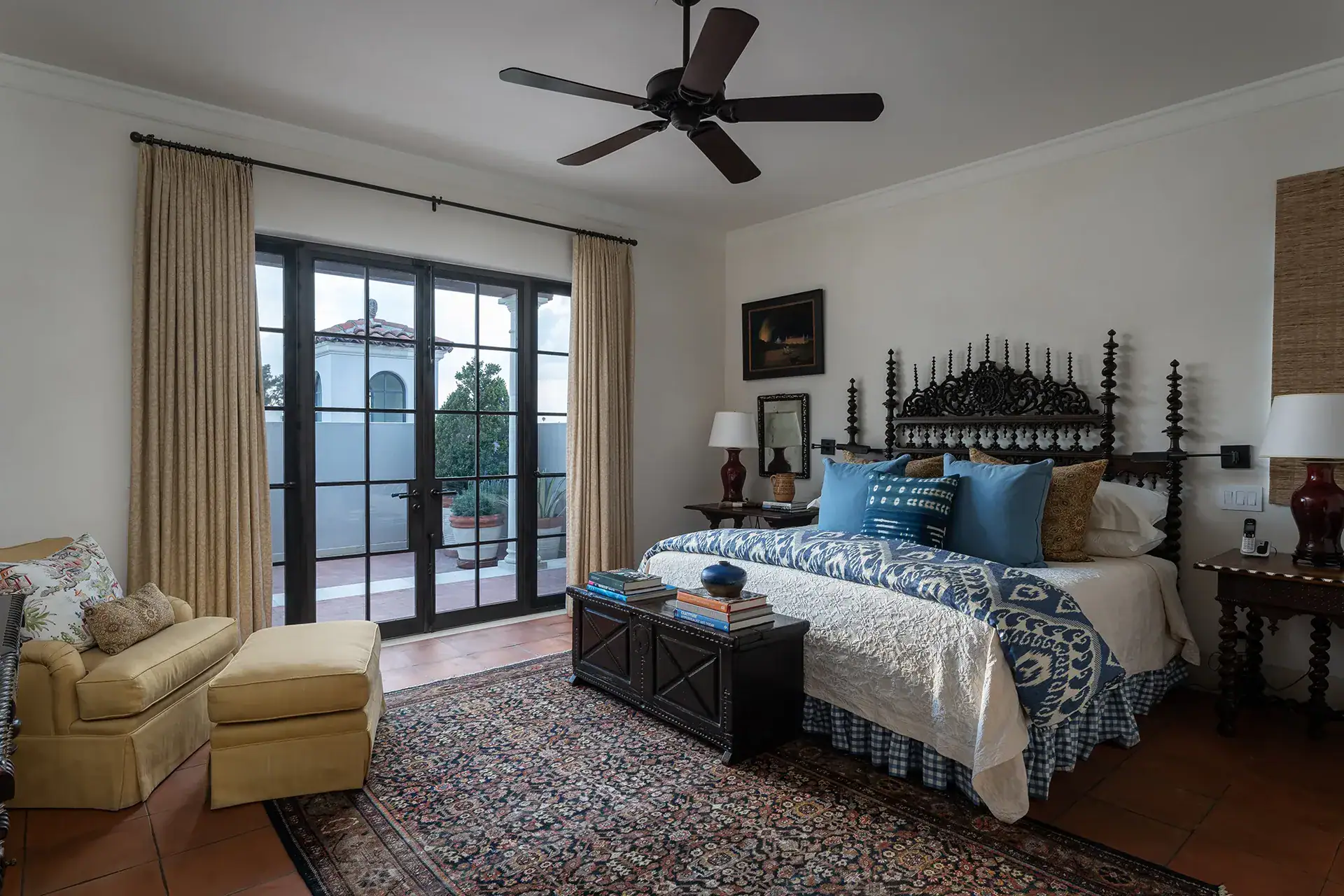 Casa Sienna, bedroom with a carved wood bed, blue patterned bedding and glass doors to a terrace, San Miguel de Allende