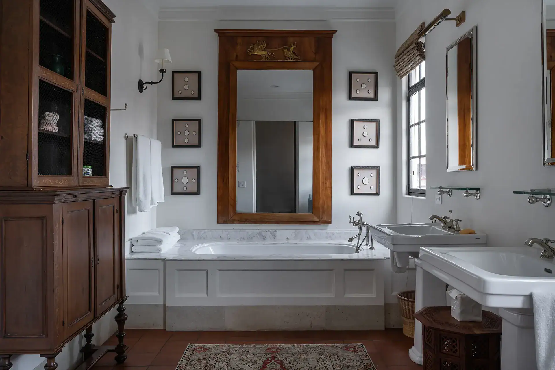 Casa Sienna, bathroom with a soaking tub, pedestal sink and a wooden display cabinet, San Miguel de Allende