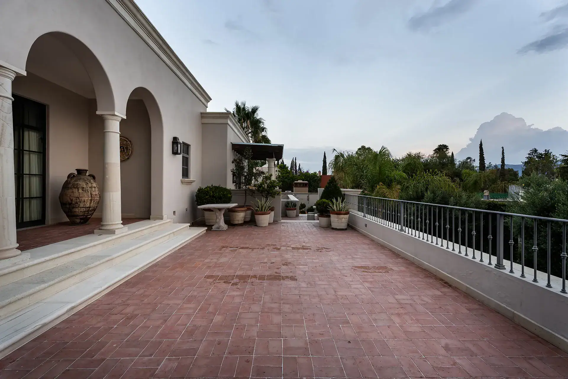 Casa Sienna, brick terrace with a balustrade and views toward trees and distant hills at dusk, San Miguel de Allende