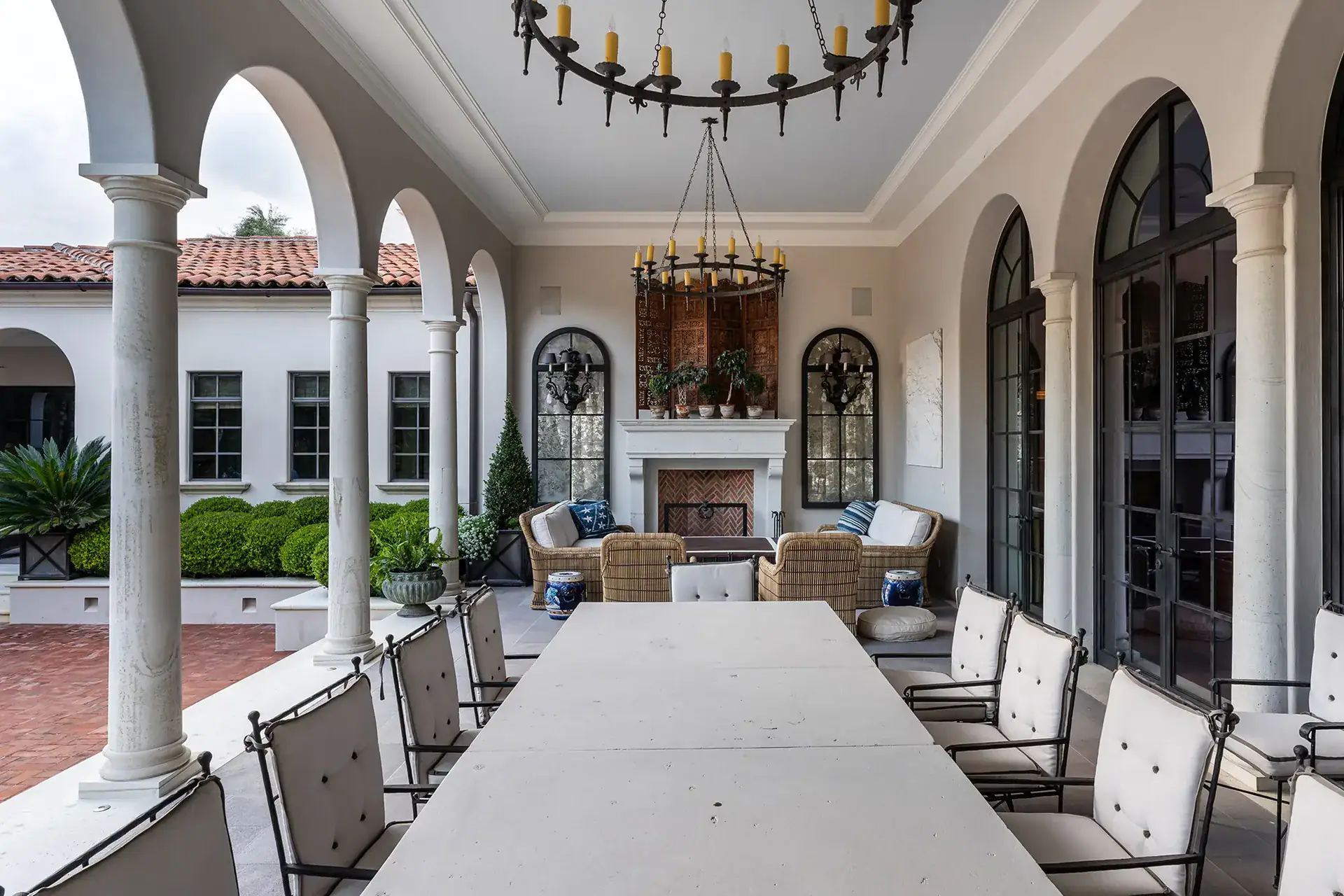 Casa Sienna, covered loggia with a long table, upholstered chairs and a fireplace seating area, San Miguel de Allende